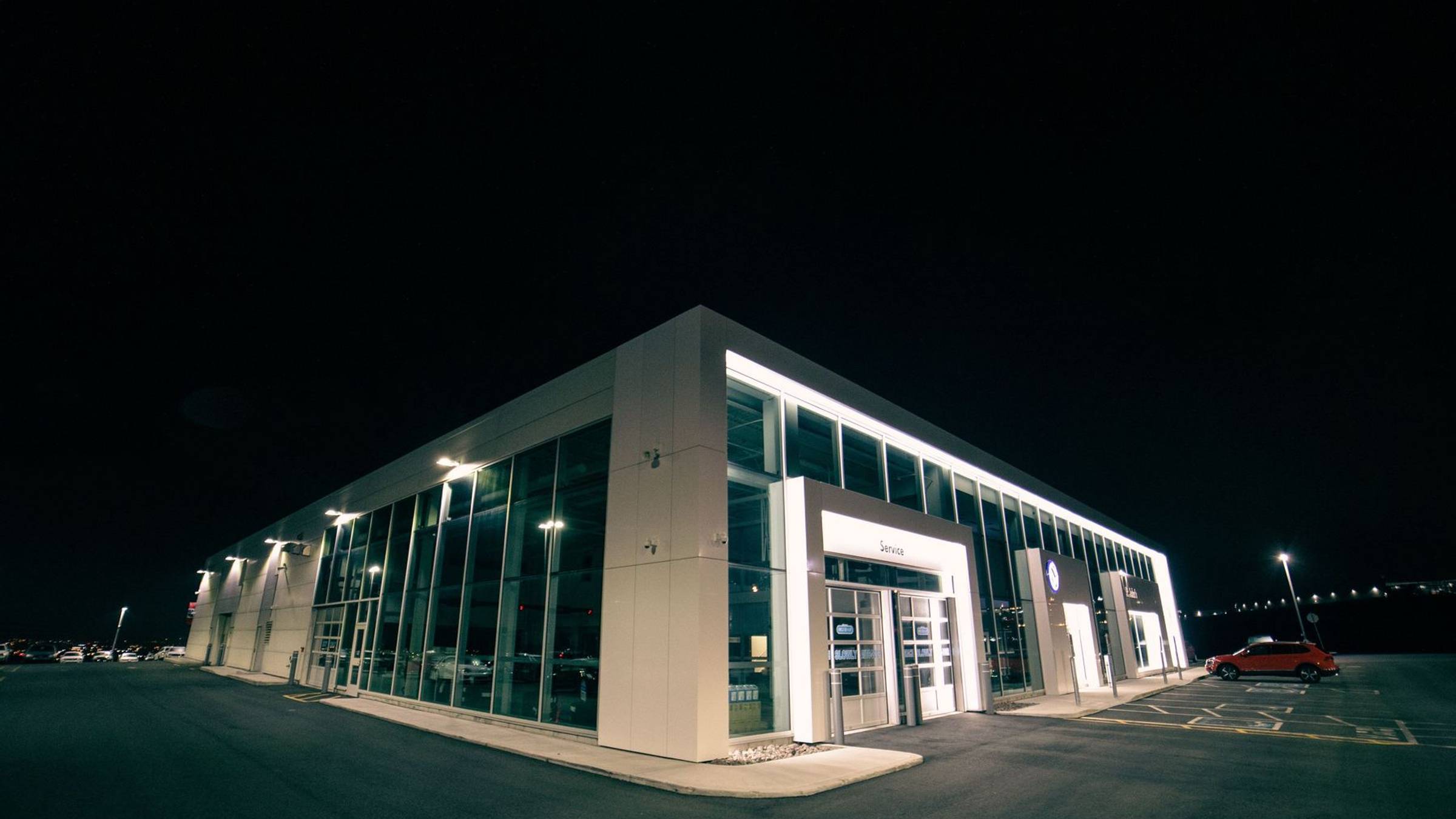 Commercial property with an illuminated façade and parked vehicles at night
